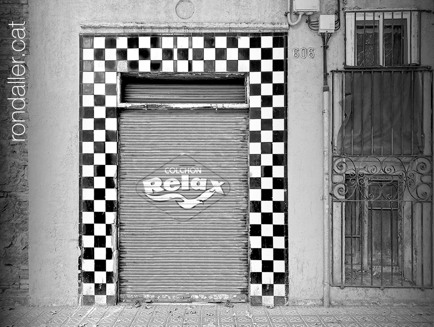 Vista de l'enrajolat blanc i negre de la façana d'una botiga abandonada a l'Eixample.