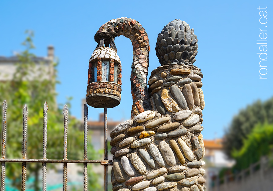 Fanal en una cantonada de l'hort, sostingut per una serp feta de mosaic.